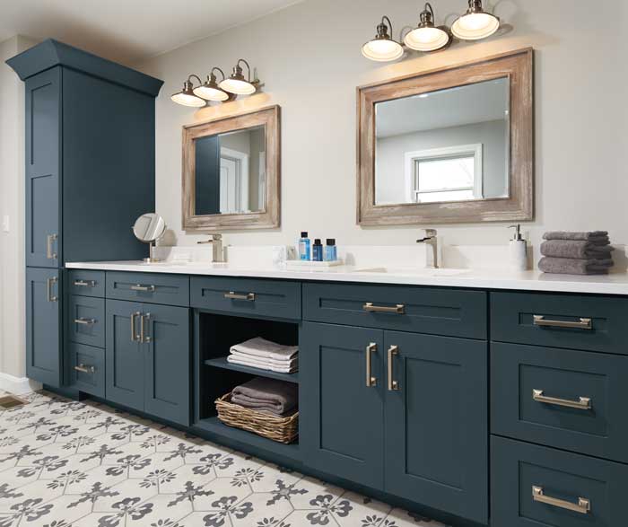 bathroom counter with blue cabinetry below two wooden mirrors